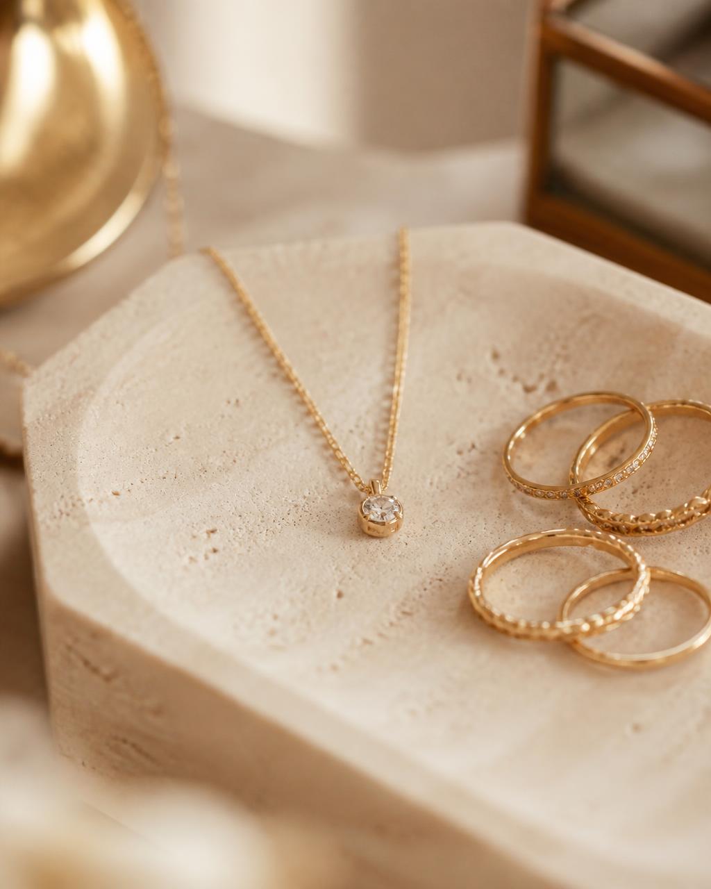 Gold necklace and rings on a stone display tray in a jewellery boutique